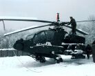 Image: A soldier removes snow from the top of an AH-64A Apache attack helicopter at Tuzla.