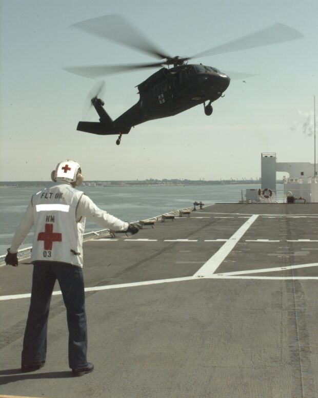 Image: A UH 60A Blackhawk helicopter flies toward the USNS Comfort AH 20.